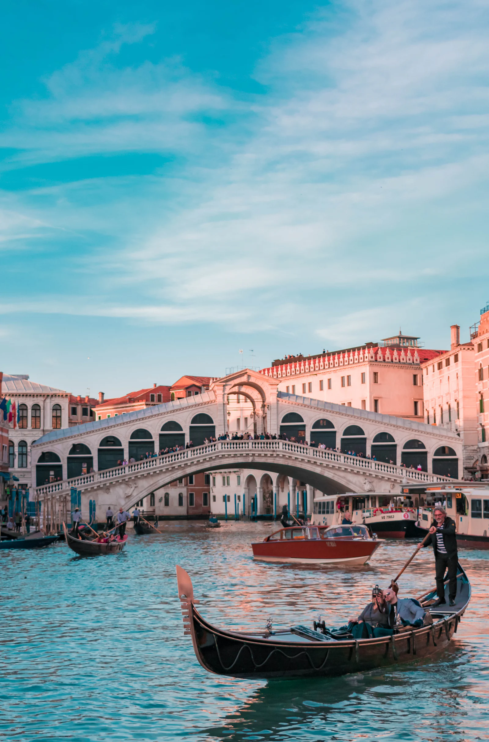 The Rialto bridge over Venice's Grand Canal, with gondolas passing beneath.